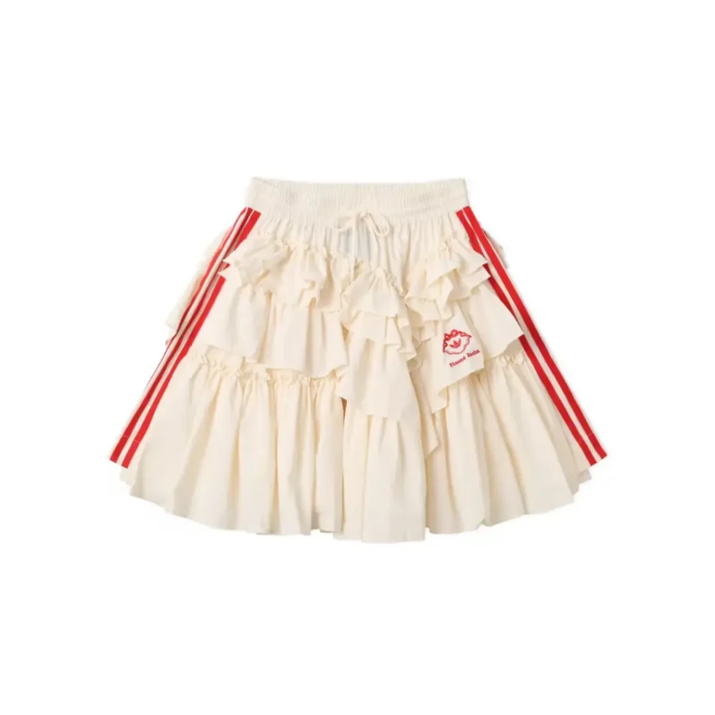 Cream ruffled skirt with red side stripes, elastic drawstring waist, and small red logo patch on a white background