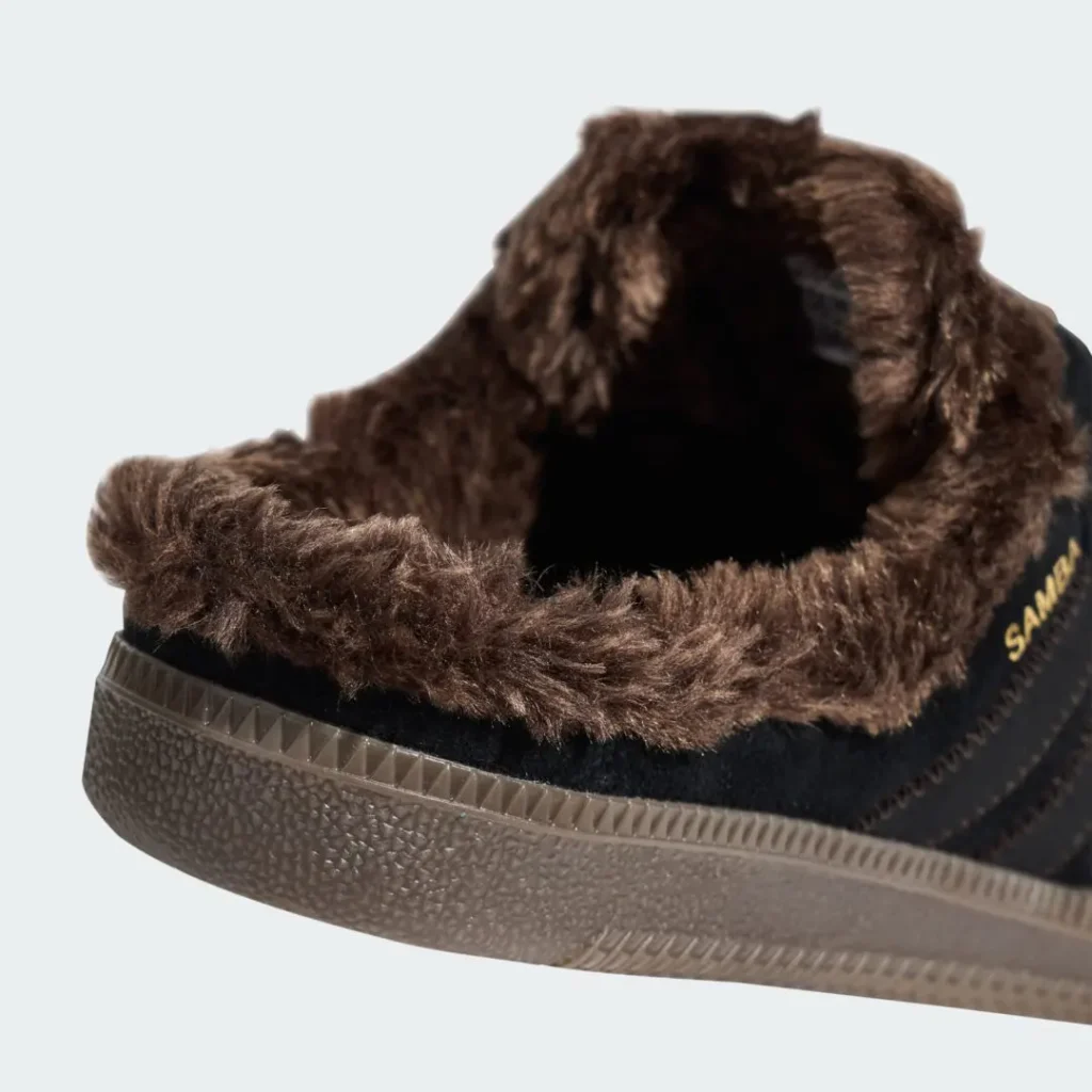 Close-up of a black sneaker with a thick brown furry lining and textured brown rubber sole against a pale background