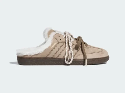 Tan suede sneaker with white faux-fur lining, dark rubber sole, and mismatched beige and white laces on a pale background