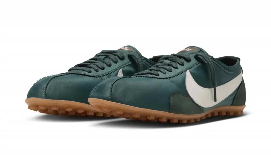 Pair of dark green low-top shoe with white swooshes, black laces and gum-colored lugged soles on white background