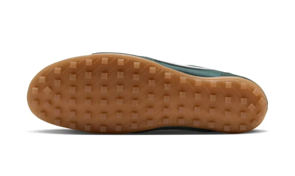 Bottom view of a shoe with a translucent gum outsole featuring a grid of raised square lugs on white background