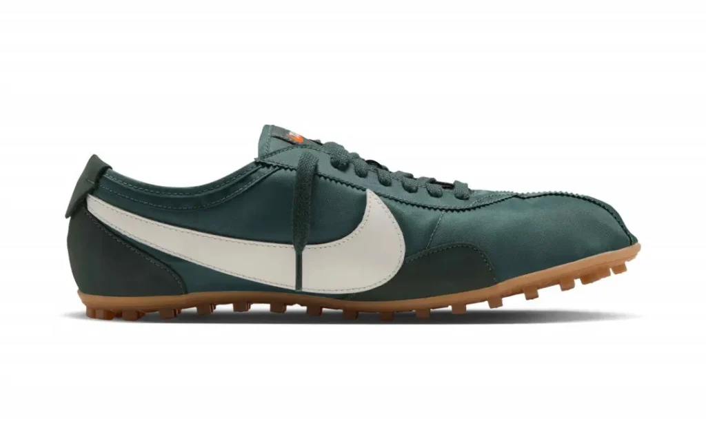Dark green Nike soccer cleat with a white swoosh, black laces, and gum-colored studded sole on white background