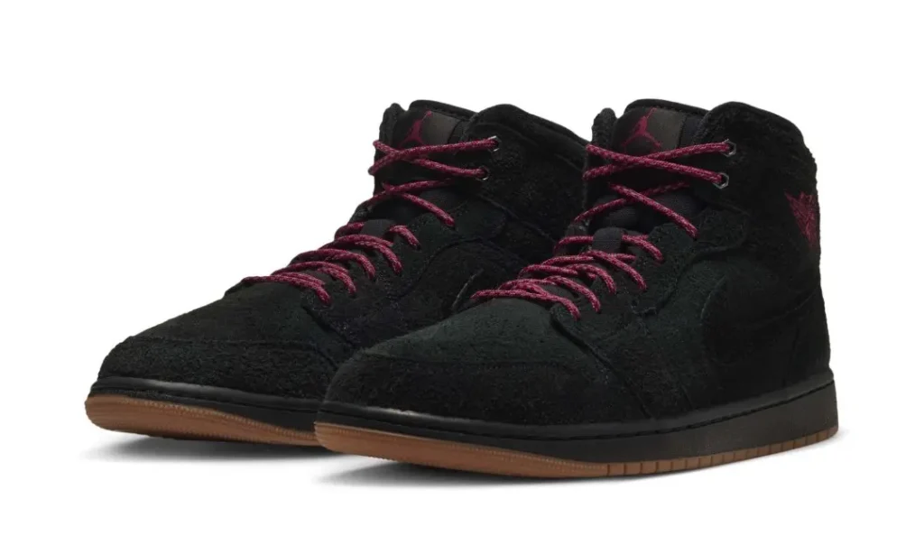 Pair of black high-top shoe with burgundy laces, textured uppers, and brown rubber soles on a white background
