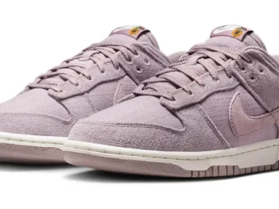 Pair of mauve Nike low-top sneakers with textured panels, white midsoles, and sunflower tongue labels on a white background