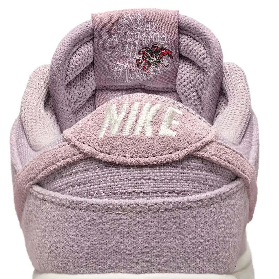Close-up of a mauve Nike shoe with a fuzzy texture, embroider white logo, and floral tongue graphic against a white