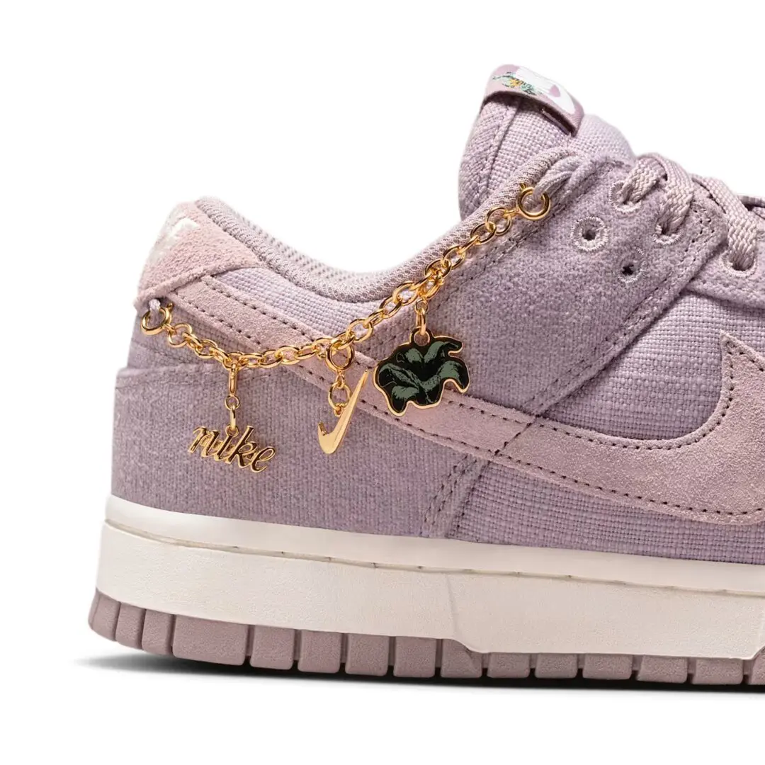 Lavender Nike Dunk sneaker with a gold chain, swoosh, script logo and black flower charm