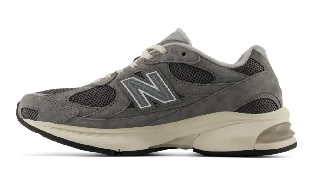 Gray New Balance sneaker with mesh panels, suede overlays, white laces, and a cream sculpted sole on a white background