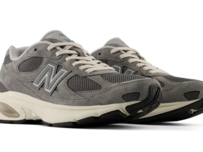 Pair of gray New Balance shoe with mesh and suede uppers, cream laces and midsoles on a white background