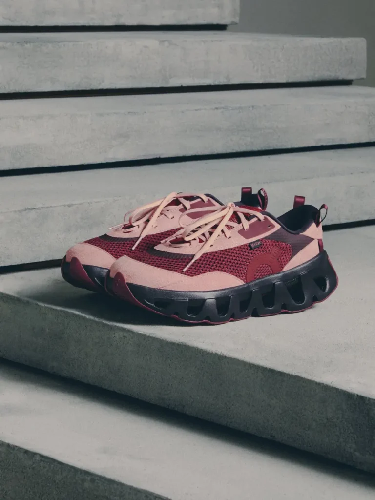 Pair of pink and burgundy athletic sneakers with chunky black soles resting on concrete steps