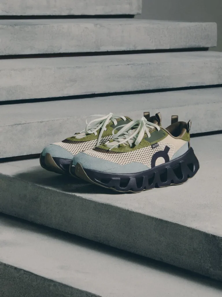 Pair of green, cream and gray mesh sneakers with white laces and chunky black soles on concrete steps