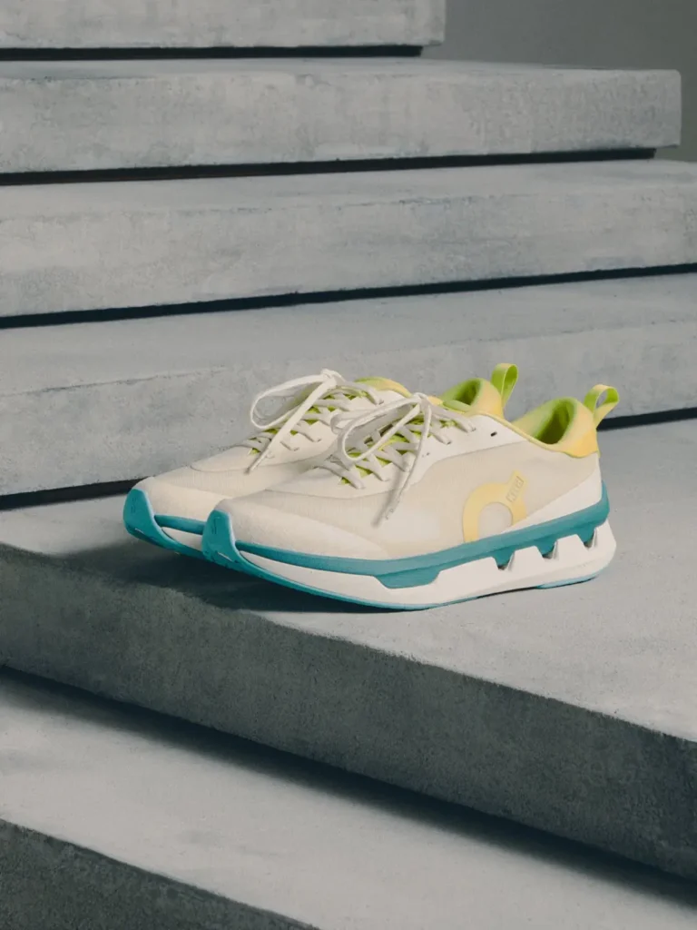 Pair of cream sneakers with turquoise soles and yellow-green accents on concrete steps