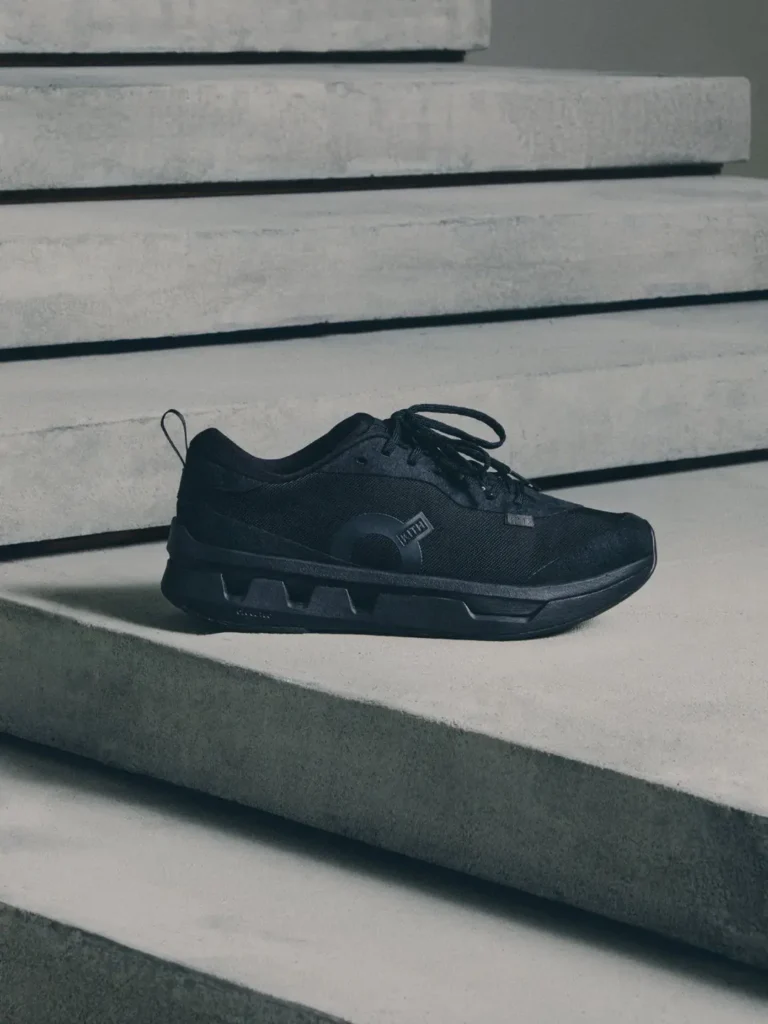 Black lace-up sneaker with a thick segmented sole rests on pale concrete steps