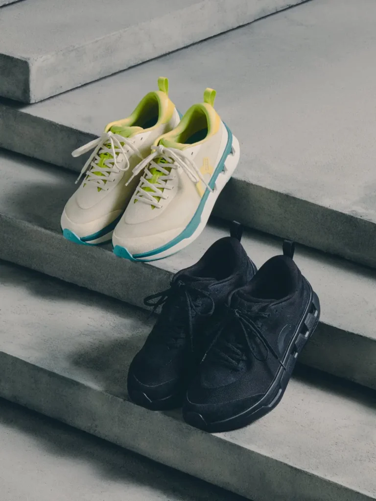 Two pairs of sneakers on concrete steps: cream shoes with lime-green lining and teal soles behind black sneakers