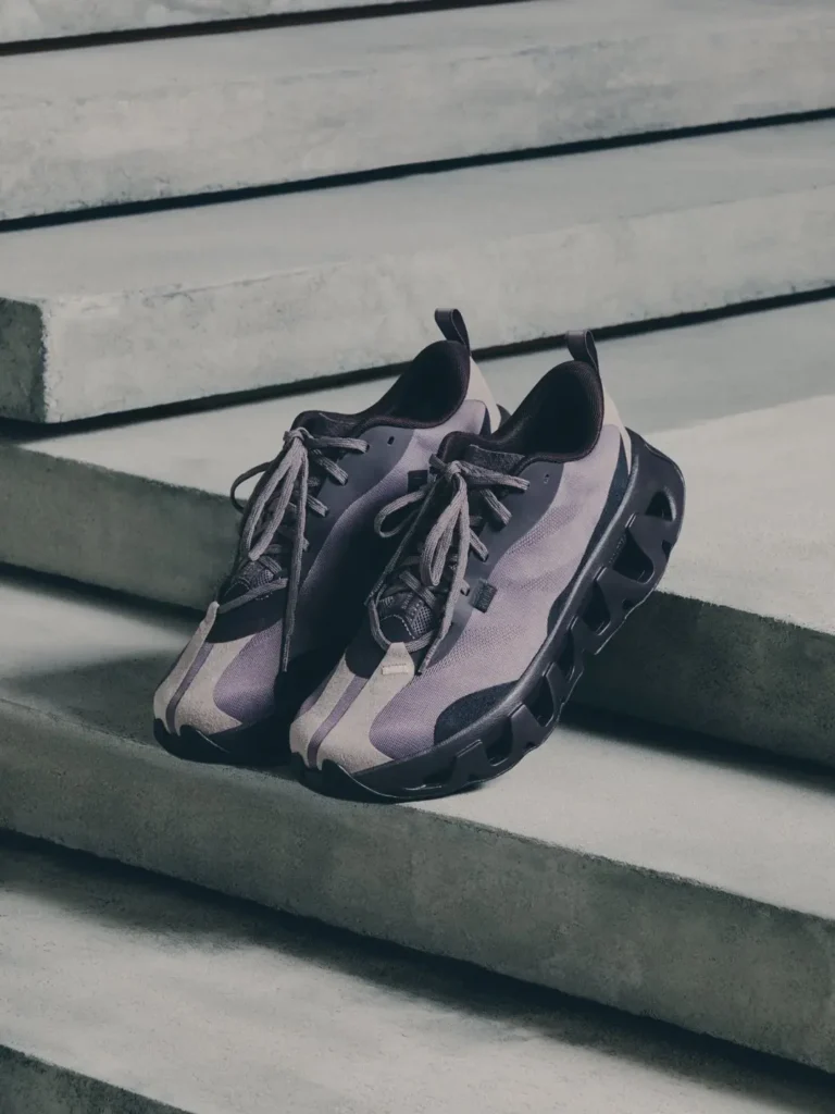 Pair of gray and black sneakers with thick sculpted soles resting on concrete steps