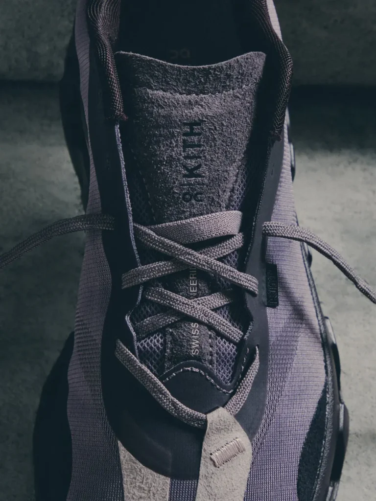 Close-up of a gray running shoe with textured fabric, crisscrossed laces, and visible “SWISS ENGINEERING” text