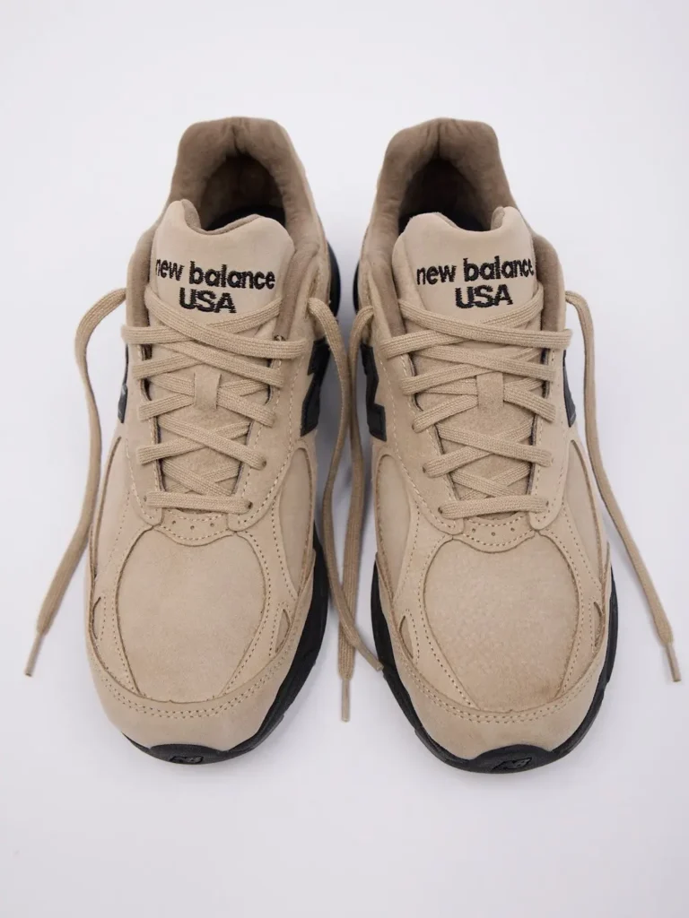Pair of beige New Balance sneakers viewed from above, with loose laces and black soles