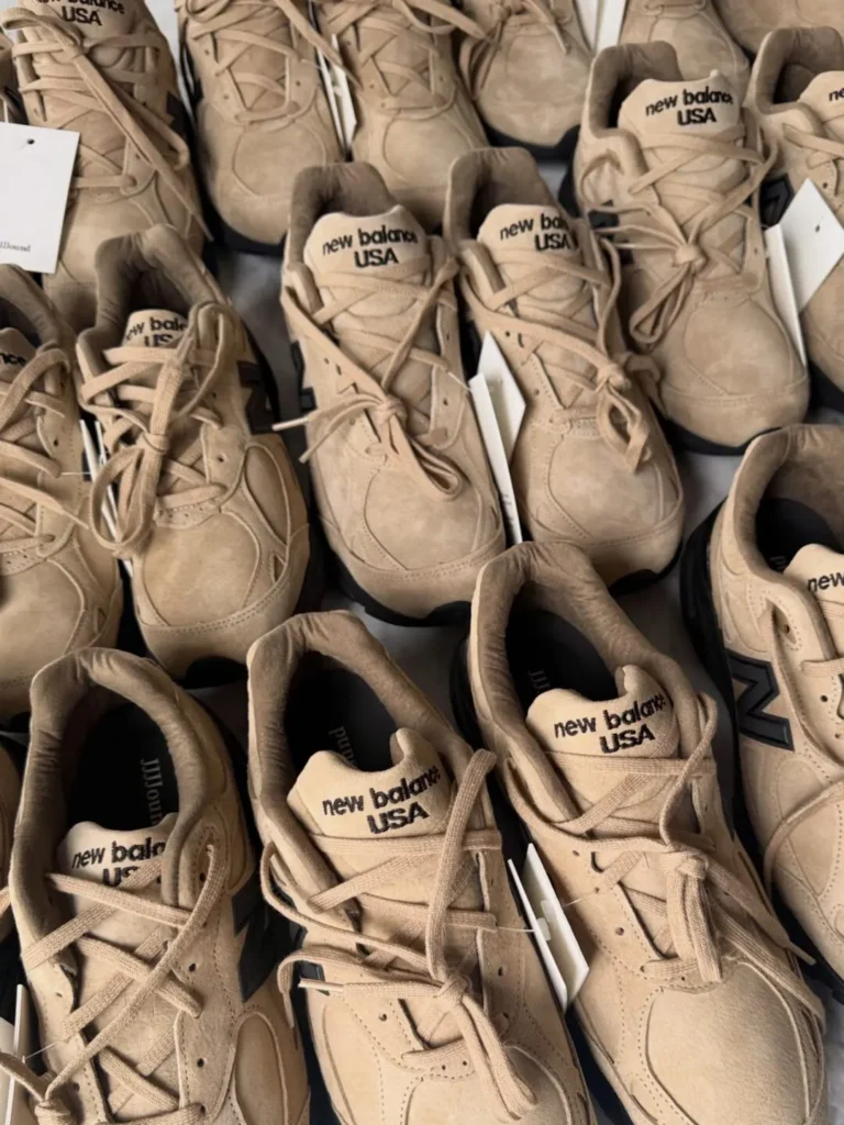 Rows of beige New Balance sneakers with laces and tags arranged closely together