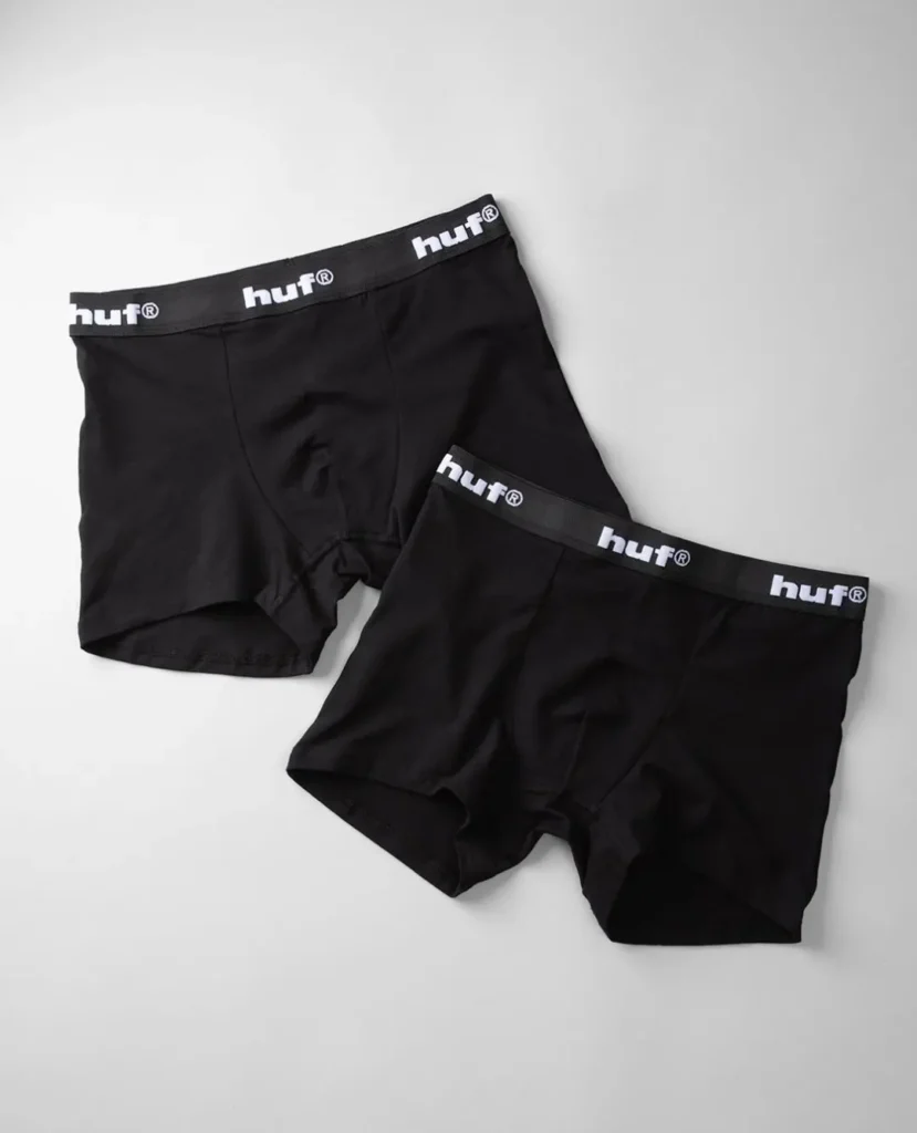 Two black boxer briefs with white HUF logos on the waistbands, arranged on a light gray background