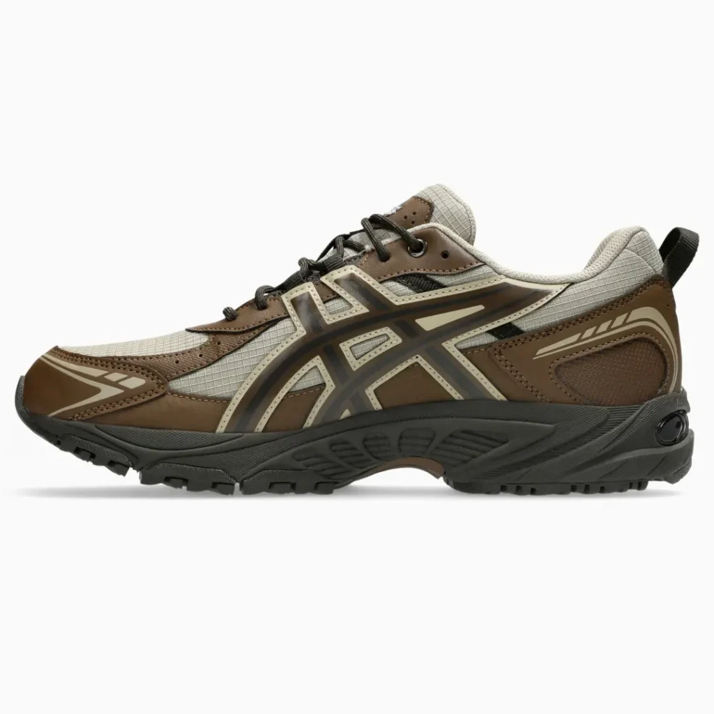Side view of a brown and gray trail sneaker with black laces, layered panels, and a rugged black sole on white background