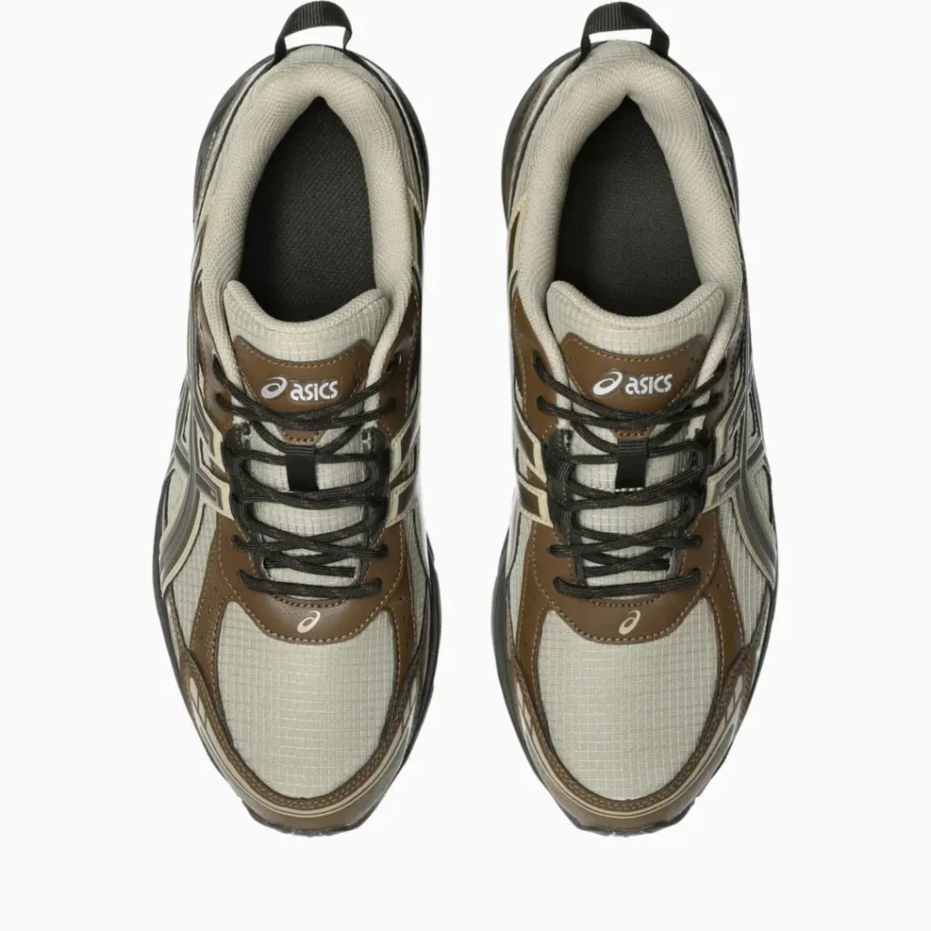 Top-down view of paired ASICS sneakers with brown and beige mesh uppers, black laces, and padded collars on a white
