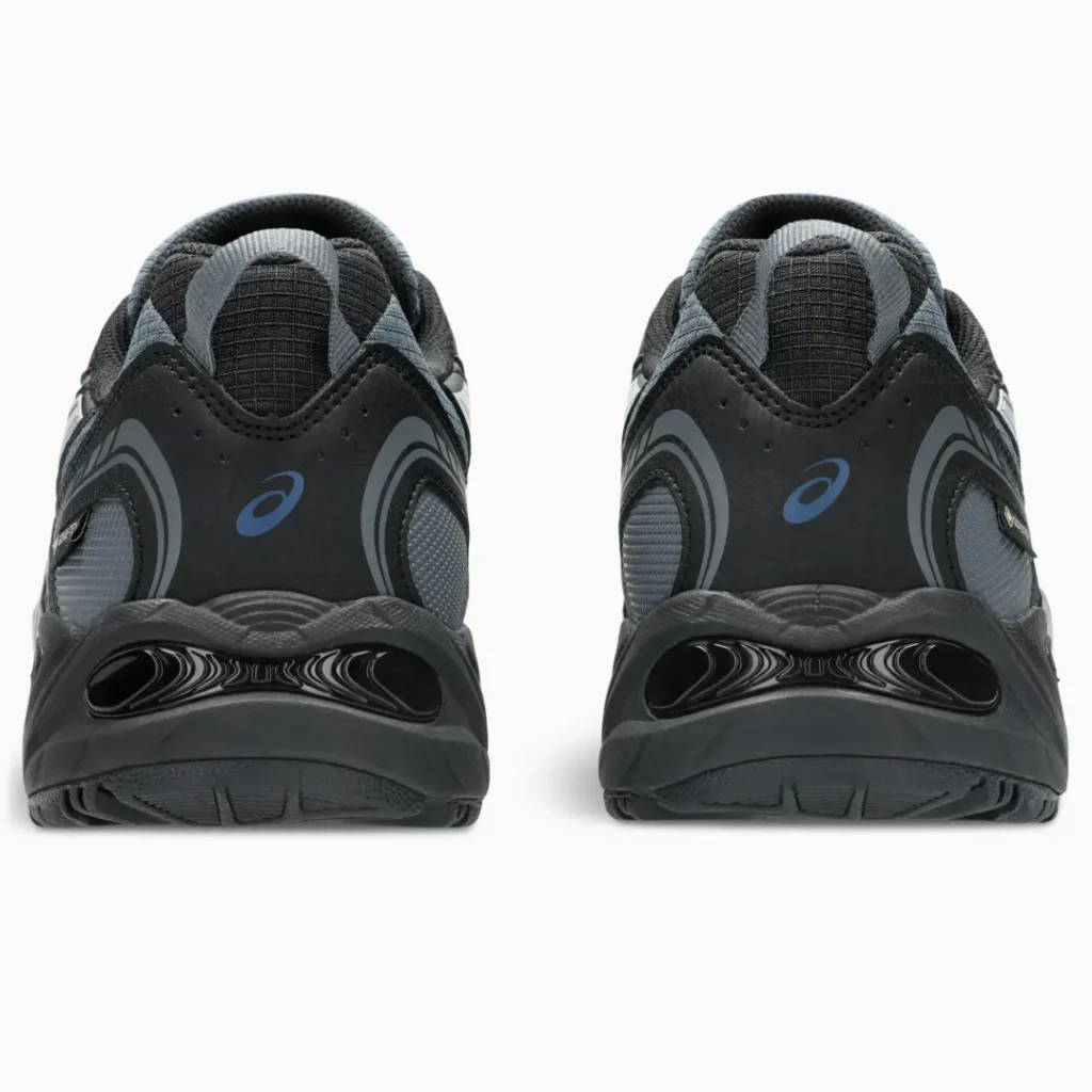 Rear view of a pair of black and gray ASICS sneakers with blue logos on a white background