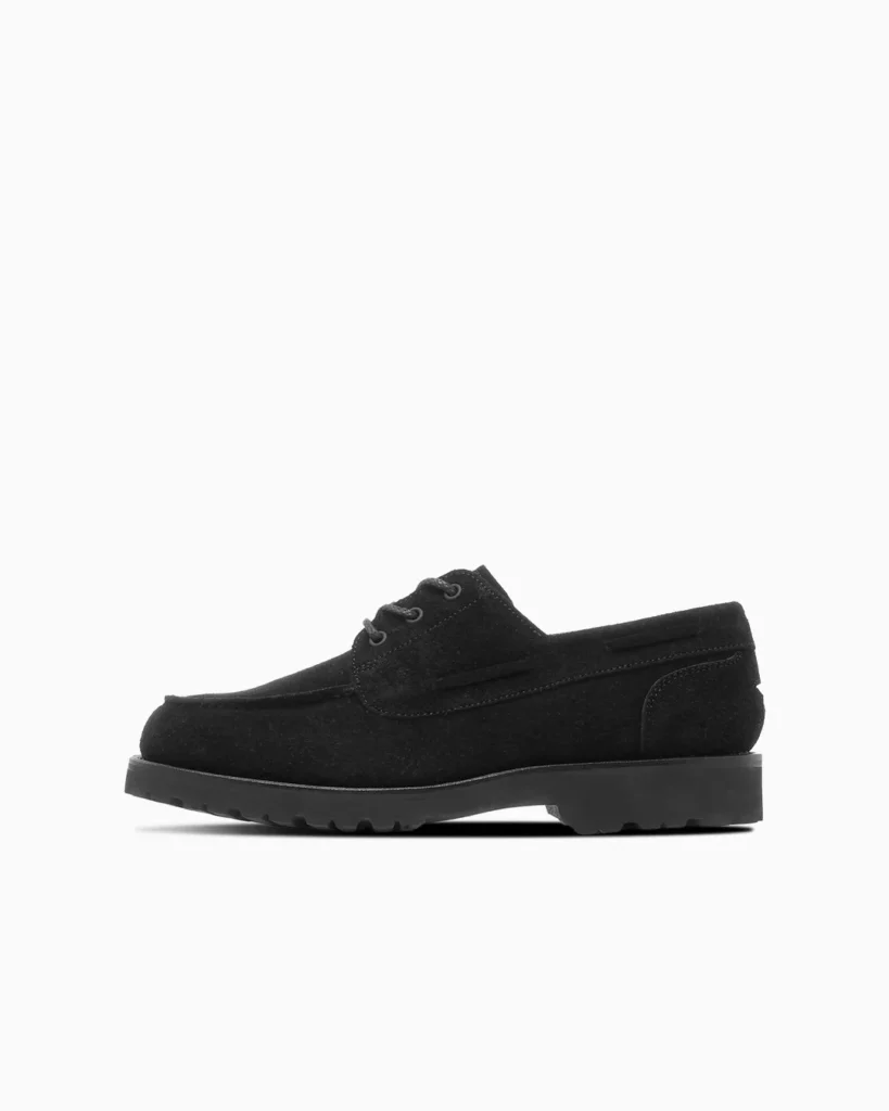 Black low-top lace-up shoe with moc-toe stitching and thick lugged sole, shown in side profile on white background