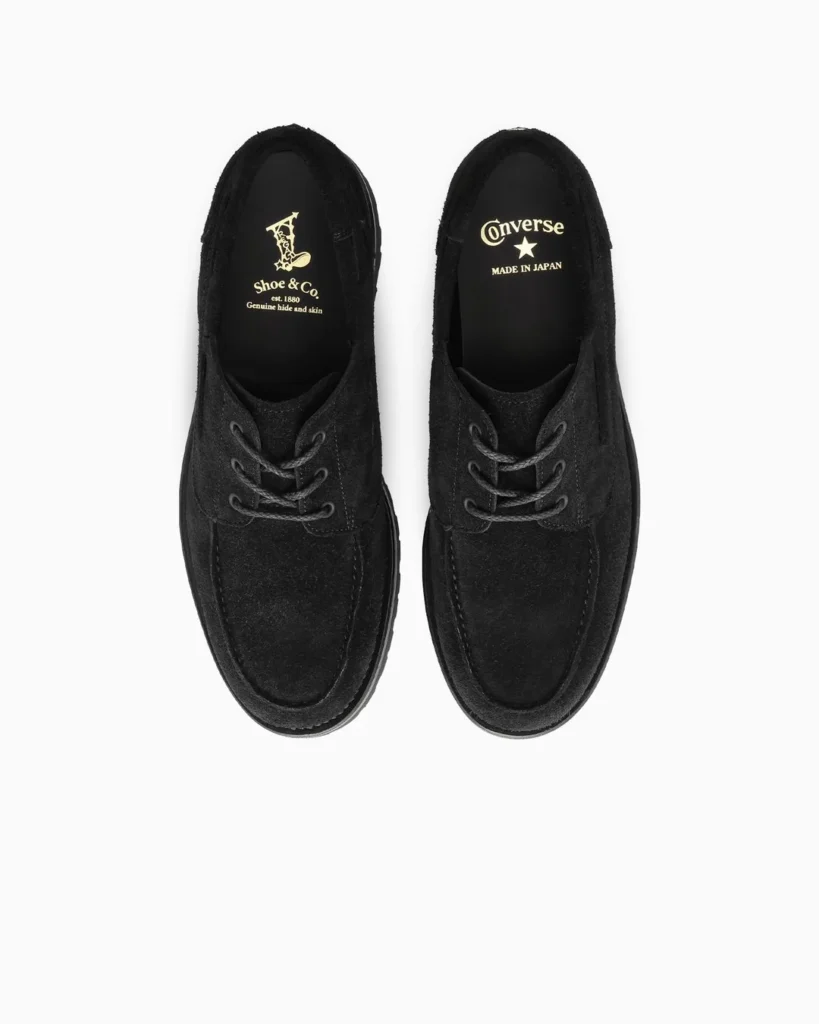 Pair of black low-top shoes with moccasin-style stitching and laces, shown from above on a white background