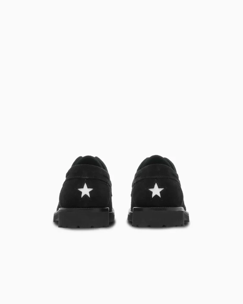 Pair of black low-top shoes viewed from the back, each featuring a white star and chunky lugged soles on a white background