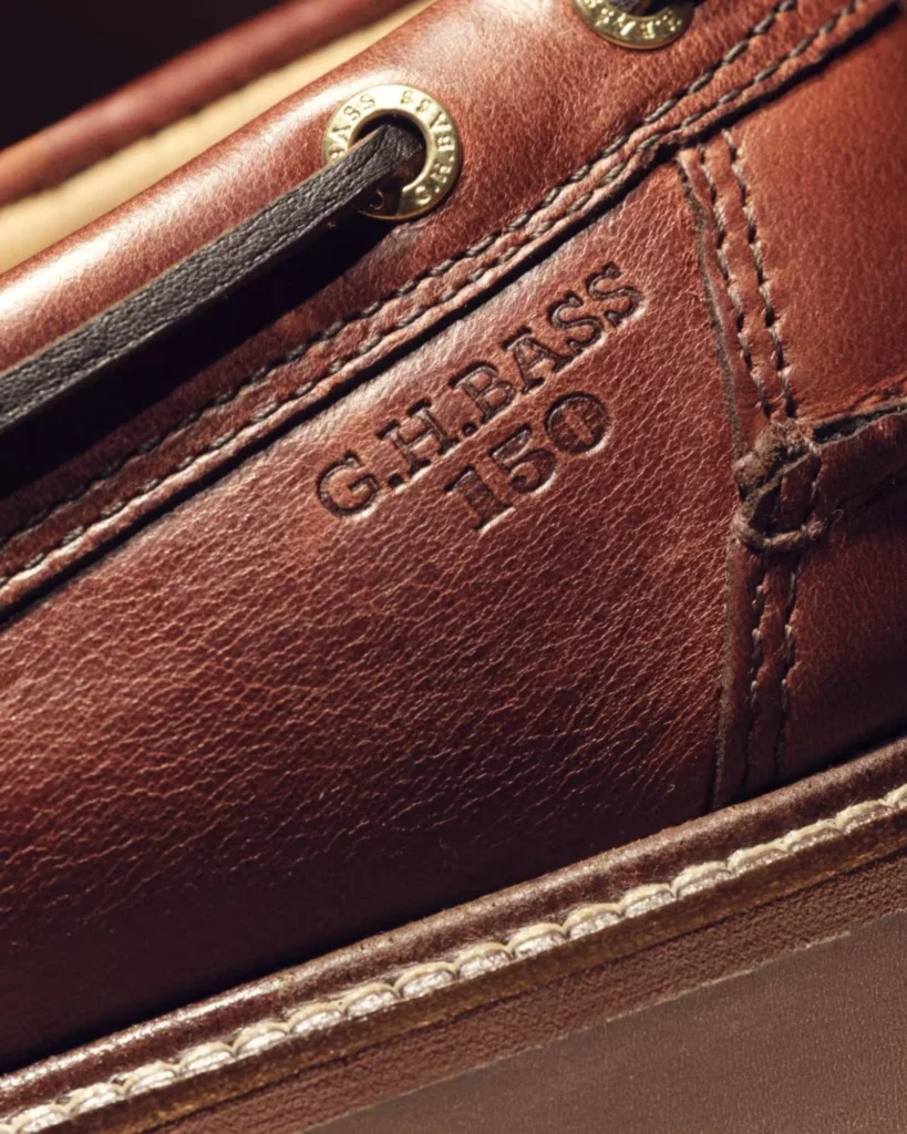Close-up of a brown leather G.H. Bass shoe with black laces, brass eyelets, stitched panels and embossed branding