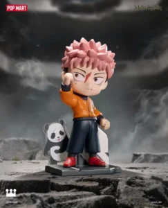 Chibi pink-haired anime figure in an orange jacket, black shorts and red shoes, raising one fist beside a panda cutout on