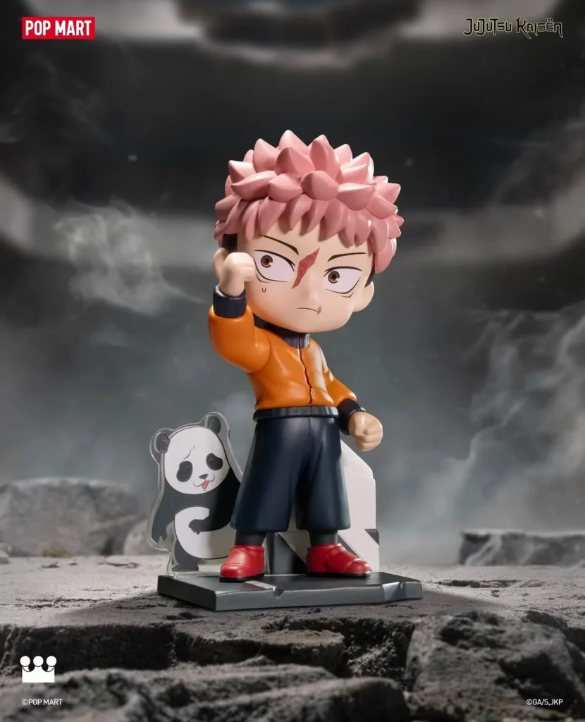 Chibi pink-haired anime figure in an orange jacket, black shorts and red shoes, raising one fist beside a panda cutout on