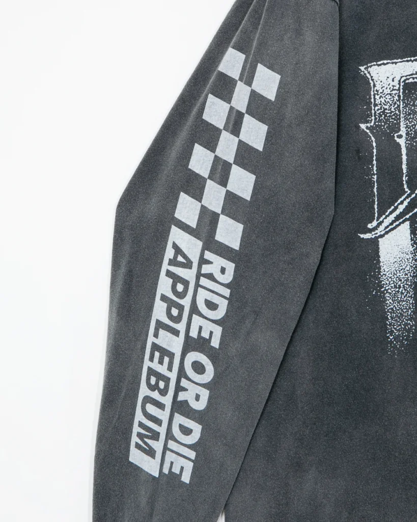 Close-up of a dark gray sleeve with a white checkerboard graphic and vertical “RIDE OR DIE APPLEBUM” text