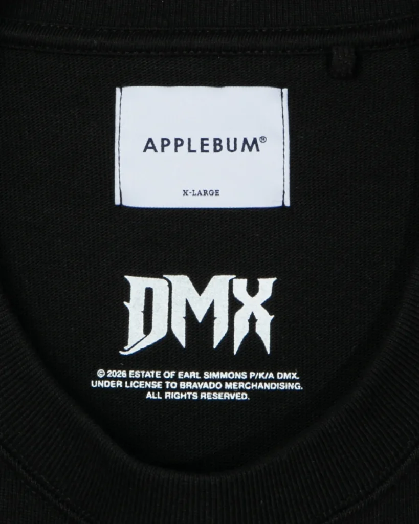 Close-up of a black garment label showing APPLEBUM, X-LARGE, and white DMX lettering with licensing text