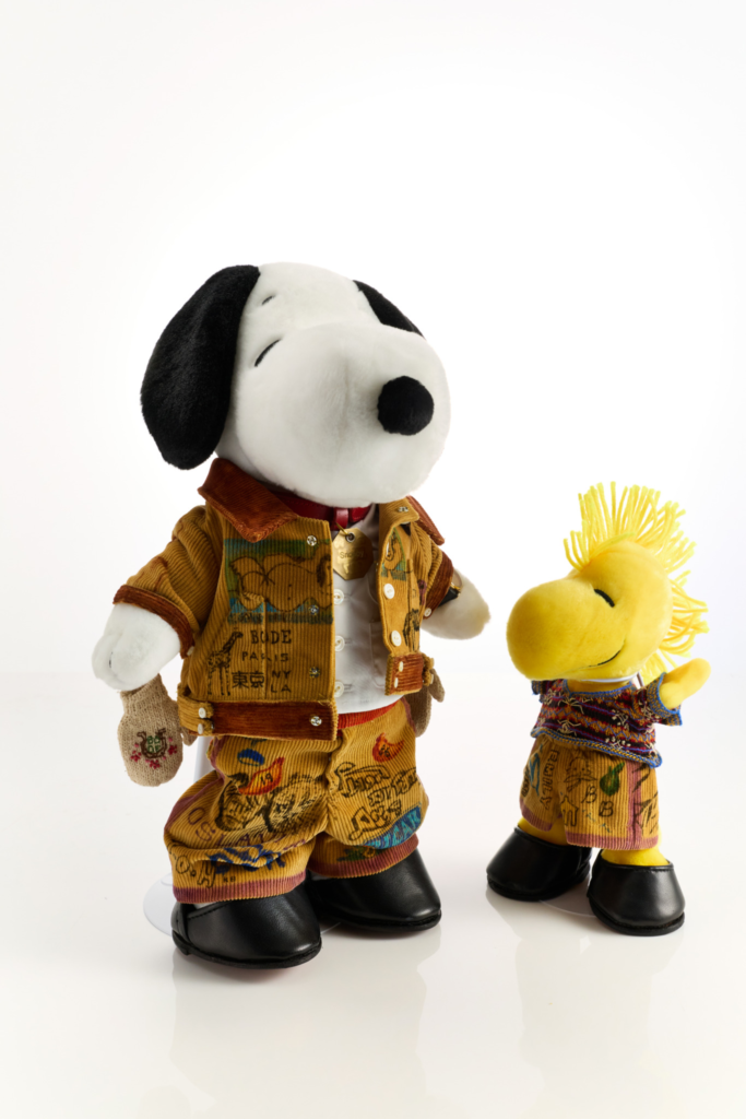Snoopy and Woodstock plush toys in colorful patchwork corduroy outfits and black shoes, posed against a white background