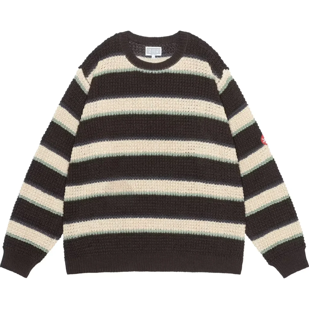 Striped black, cream and pale green knit sweater with crew neck, ribbed cuffs and small red sleeve tag on white background