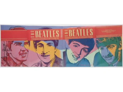 Open magazine spread with colorful illustrated portraits of four men beneath a red banner reading “The Beatles”