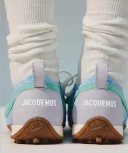Close-up of white Jacquemus shoe with lavender panels, mint and blue accents, and brown texture sole pair with