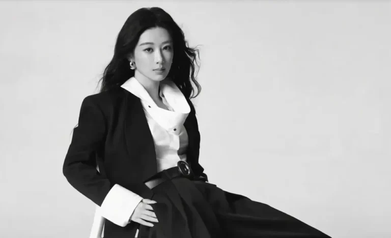 Black-and-white portrait of Yang Zi seated in a black suit with a white shirt and wide cuffs