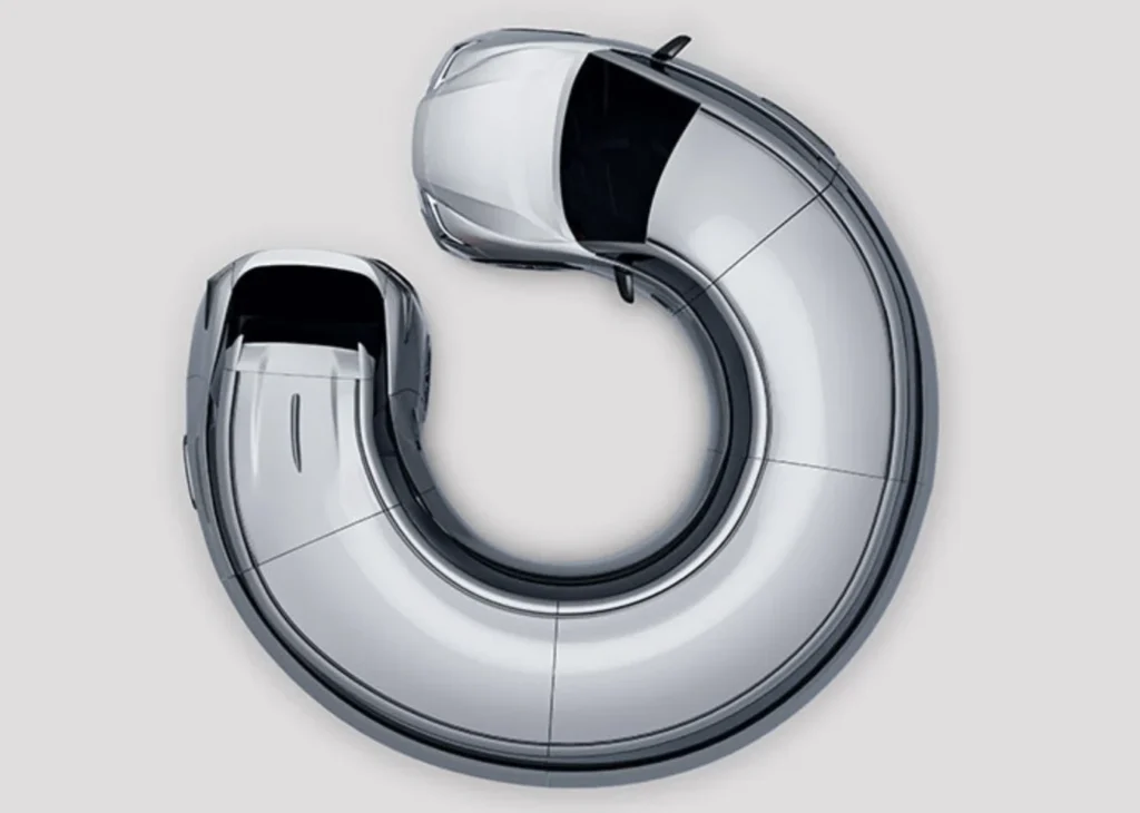 Two silver car bodies curve into a U-shaped sculptural form, viewed from above