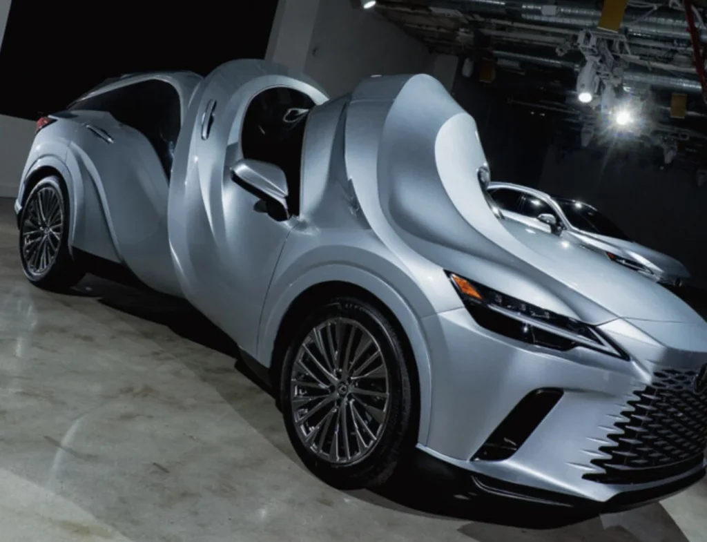 Sculptural silver Lexus with two fused front ends and curved bodywork displayed indoors