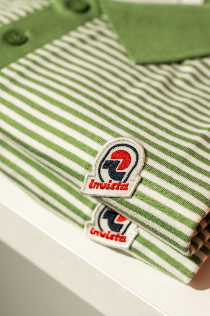 Green-and-white striped Invicta garment with embroidered logo and folded matching fabric on a shelf