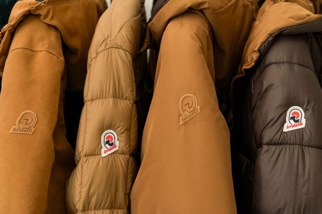 Close-up of tan and brown Invicta jackets with stitched and embroidered brand patches