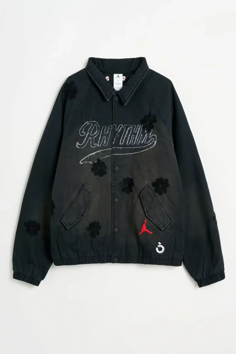 Black Jordan jacket with floral appliqués, gray NÒMARHYTHM lettering, red Jumpman logo and white emblem on white background