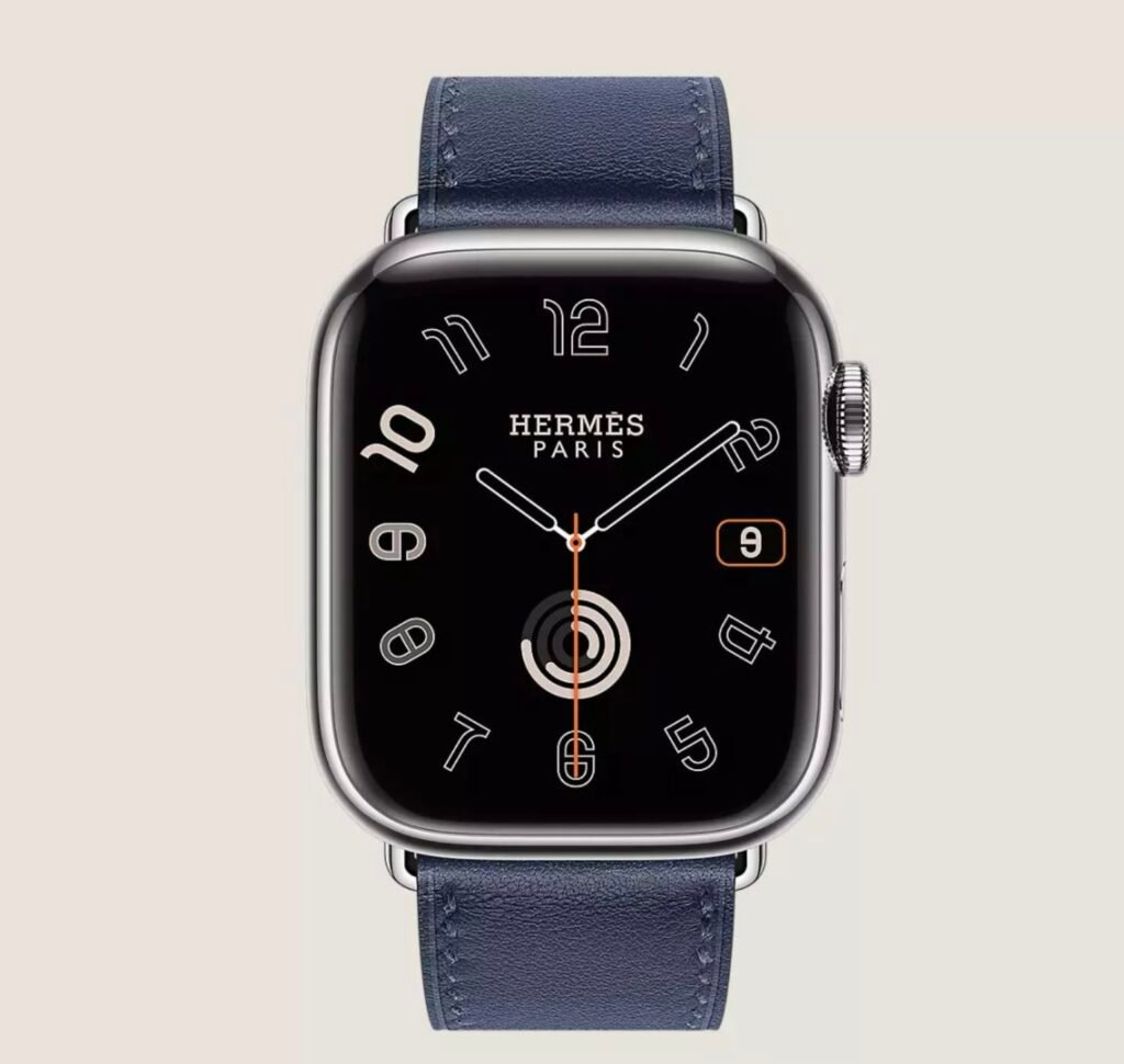 Hermès Apple Watch with navy leather band, silver case, and black dial with outlined numerals on a beige background