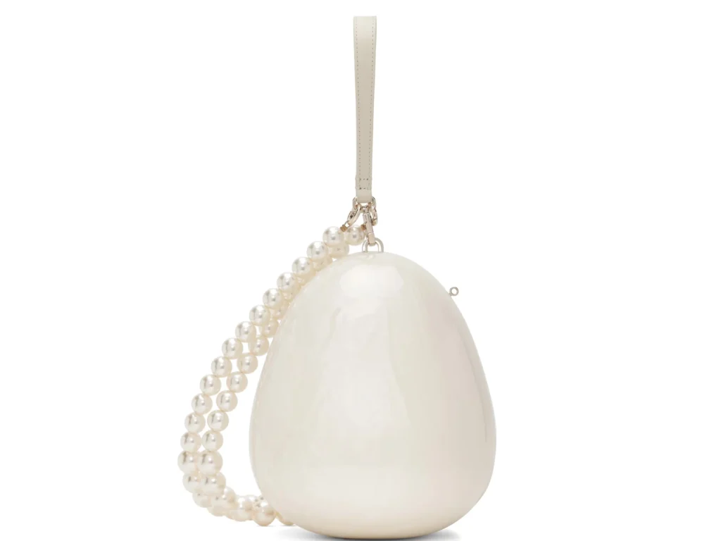 White egg-shaped handbag with a pearl-beaded strap and silver hardware against a white background