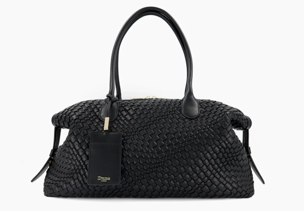 Black woven leather duffel bag with two handles and a hanging rectangular tag, centered against a white background