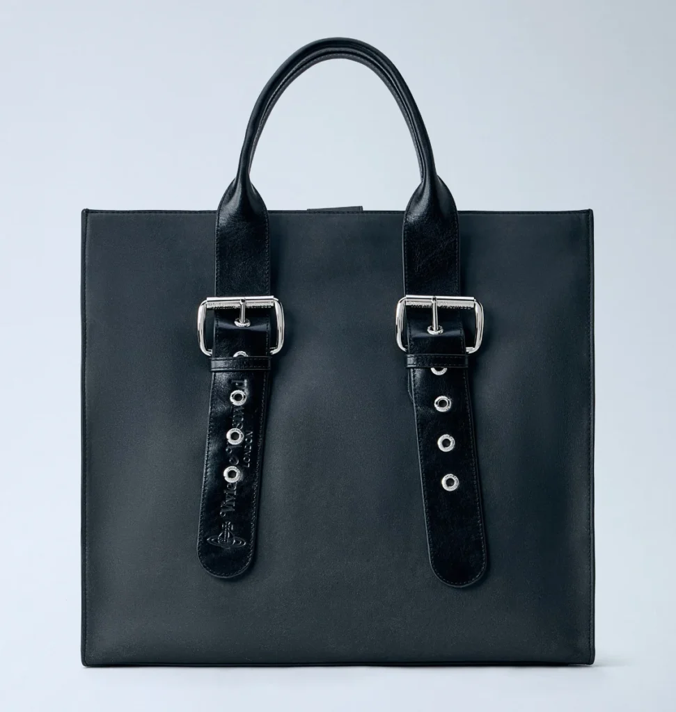 Black leather tote with two buckled straps, silver hardware, and twin handles against a pale background