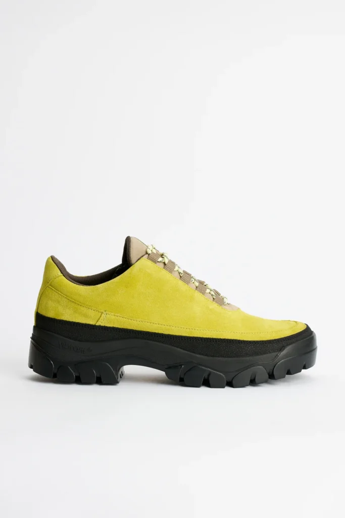 Lime green suede low-top shoe with beige laces and a chunky black lug sole on a white background