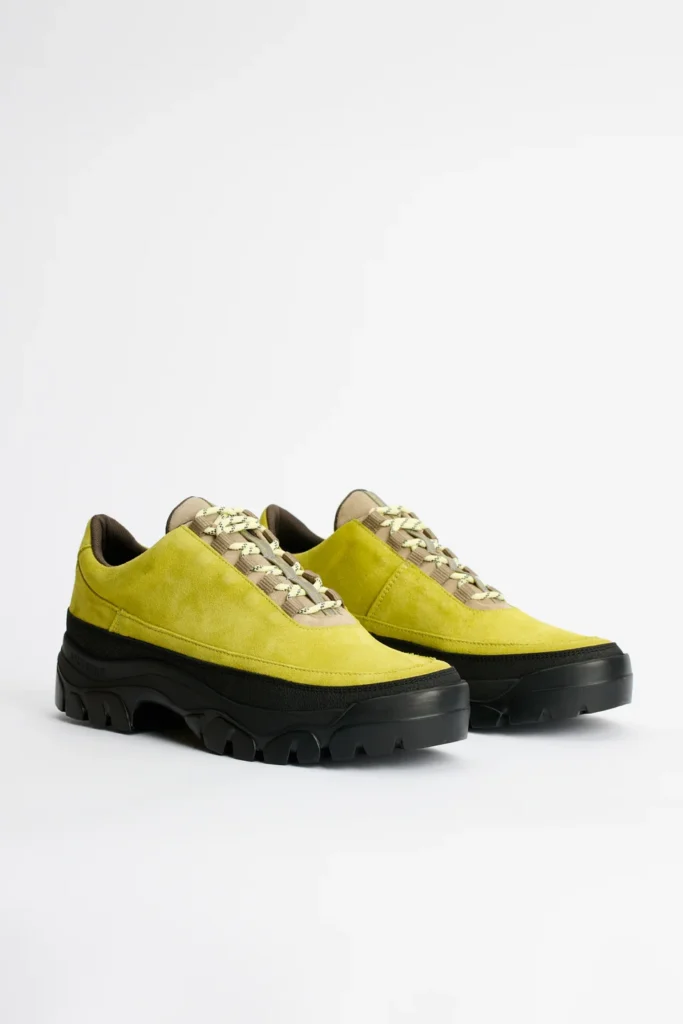Pair of lime-green suede shoe with cream patterned laces and chunky black lug soles on a white background