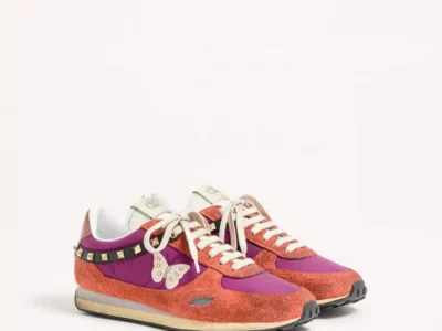 Pair of low-top Valentino sneakers in coral suede and purple fabric, with cream laces, studs, and a butterfly detail